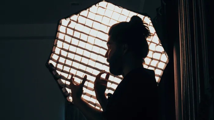 A director's silhouette against a studio softbox, mid gesture