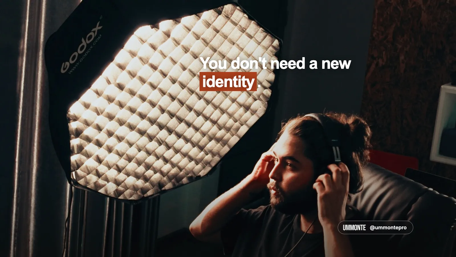 You don't need a new identity, in bold white type with 'identity' highlighted in orange, over a photo of a man adjusting headphones in front of a glowing softbox